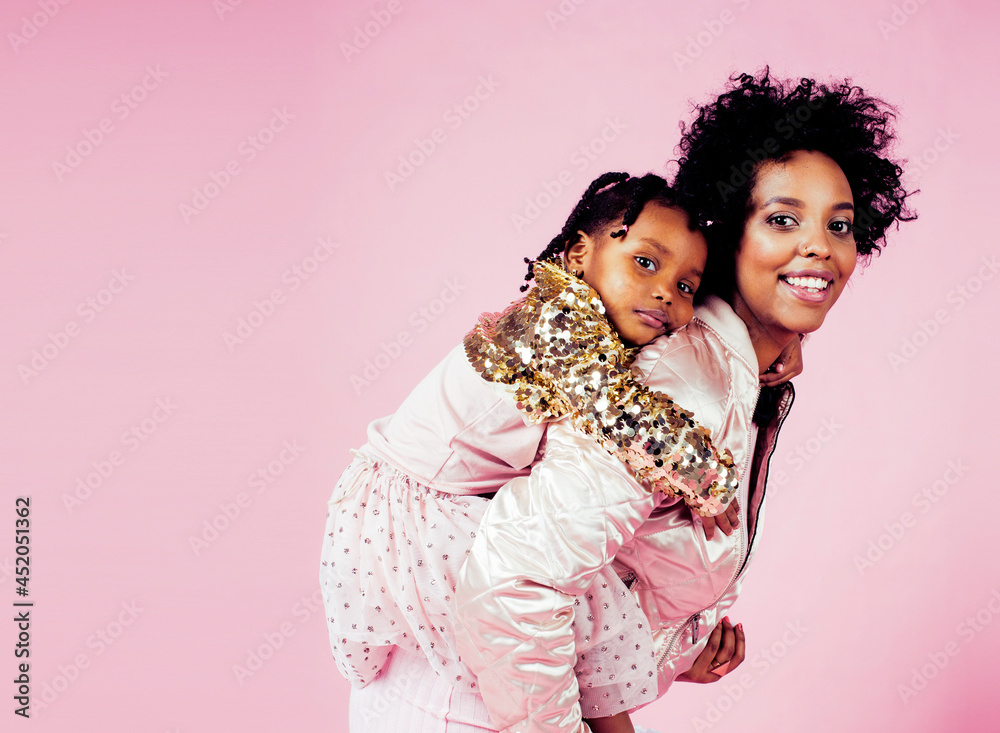 young pretty african-american mother with little cute daughter hugging, happy smiling on pink background, lifestyle modern people concept close up young pretty african-american mother with little cute daughter hugging, happy smiling on pink background, lifestyle modern people concept close up