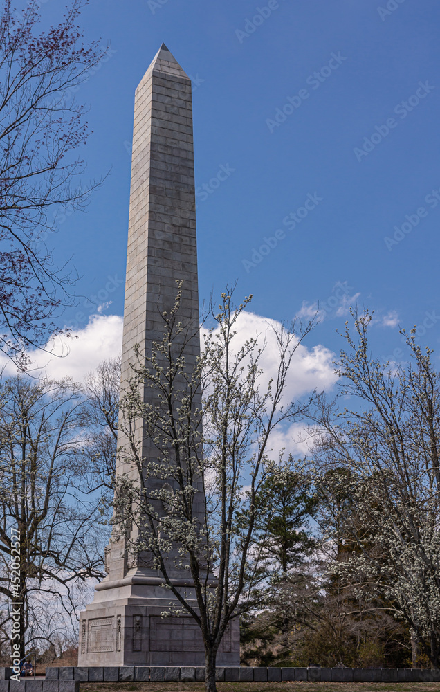 Jamestowne, VA, USA - April 1, 2013: Historic site. Tencentennial monument surrounded by blooming trees under blue cloudscape.