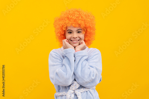 birthday or pajama party. funny kid in curly clown wig. fancy child wear home bathrobe.