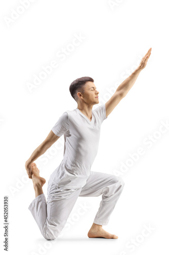 Full length profile shot of a young kneeling and practicing yoga