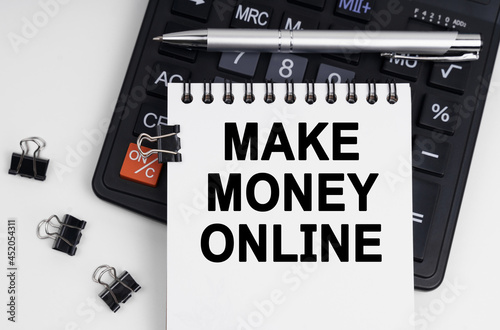 On the table is a calculator, a pen and a notebook with the inscription - MAKE MONEY ONLINE