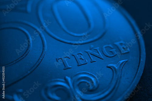 Translation: tenge. Fragment of a Kazakh coin in 50 tenge. Deep blue tinted background or wallpaper. The name of the currency in Latin. Wallpaper about Kazakh economy, money and banking. Macro