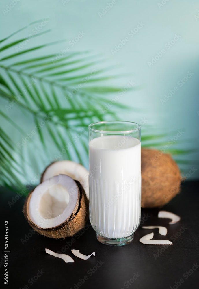 a glass of coconut milk with coconut halves and a palm leaf a glass of coconut milk with coconut halves and a palm leaf
