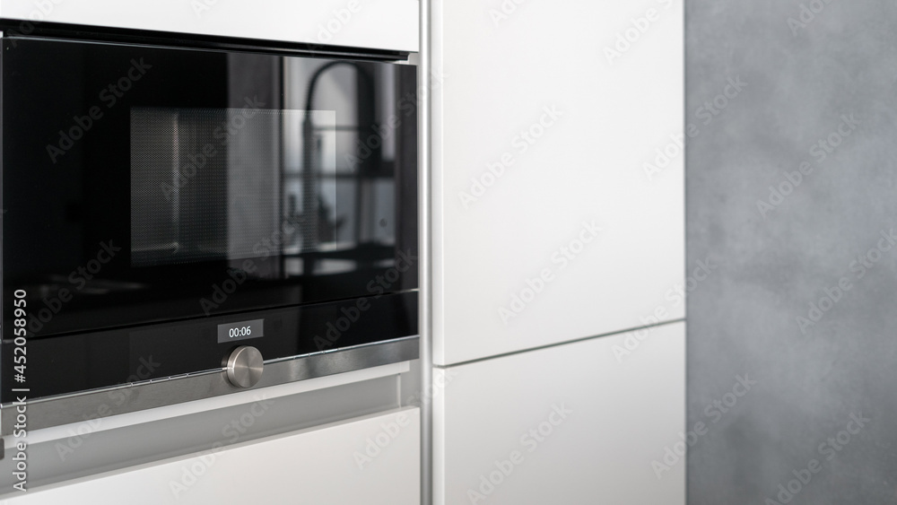 Spacious white cupboard with built-in glossy black microwave Spacious white cupboard with built-in glossy black microwave