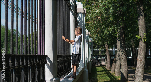A little boy tries to climb a fence