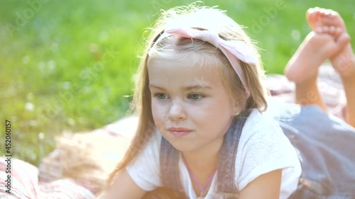 Portrait of pretty child girl resting outdoors in summer park.