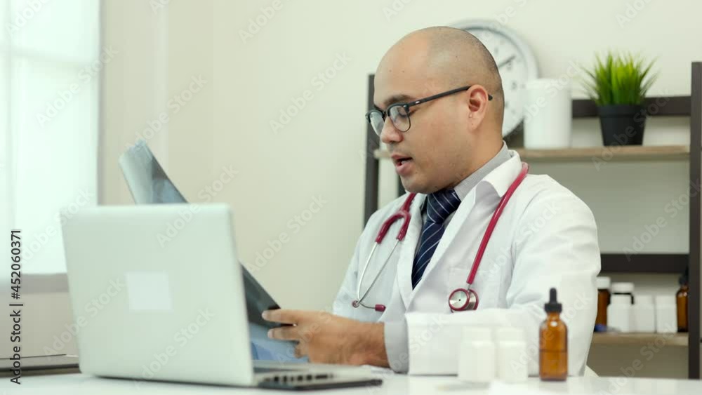 Doctor talks to patient via online video conferencing with laptop holding x-ray film. Explain about taking medications to treat illnesses.
Doctor talks to patient via online video conferencing with laptop holding x-ray film. Explain about taking medications to treat illnesses.