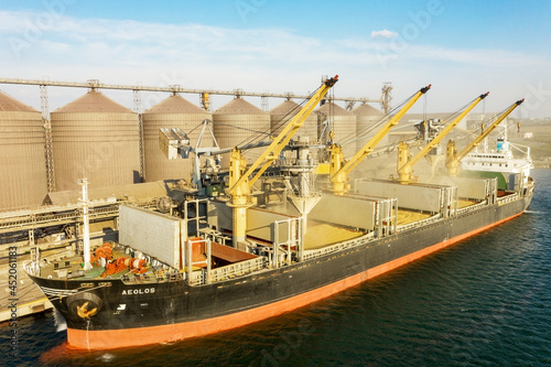 Canvas Print ODESSA, UKRAINE - August 9, 2021: Loading grain into holds of sea cargo vessel through an automatic line in seaport from silos of grain storage