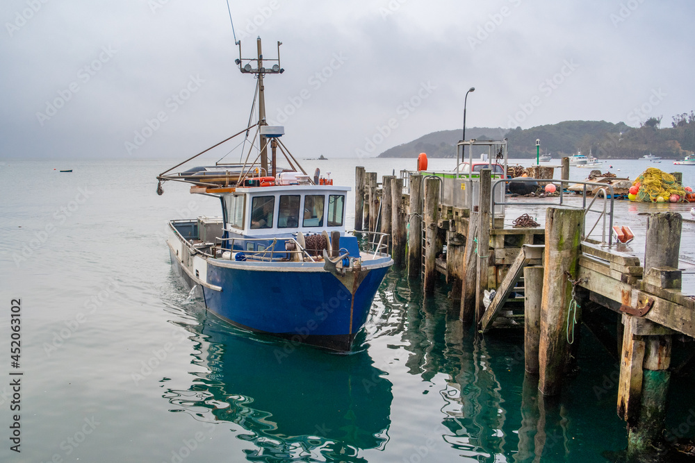 A fishing boat docked at the wharf, floats on the still sea, waiting for the next trip out on the ocean