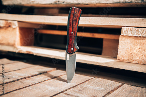 Folding pocket knife with wooden handle. A small knife on a wooden surface.