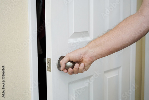 Man's hand pulling open a closet door.