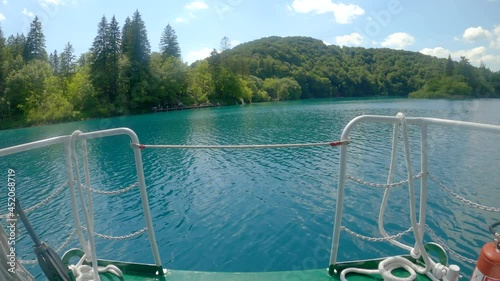 POV: Riding across the calm emerald lake in an empty boat transporting tourists around Pltivice national park. Scenic first person view of a boat ride in Plitvice park closed due to coronavirus. photo
