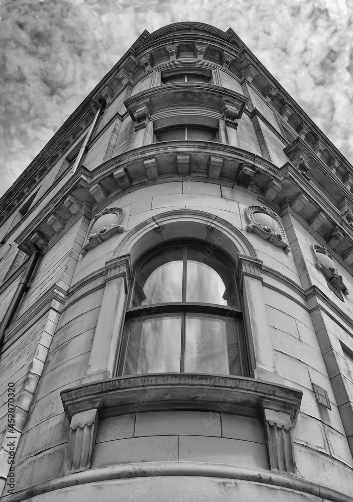 monochrome perspective view of a 19th century tall stone neoclassical building with ornate curved windows in the little germany business district of bradford west yorkshire