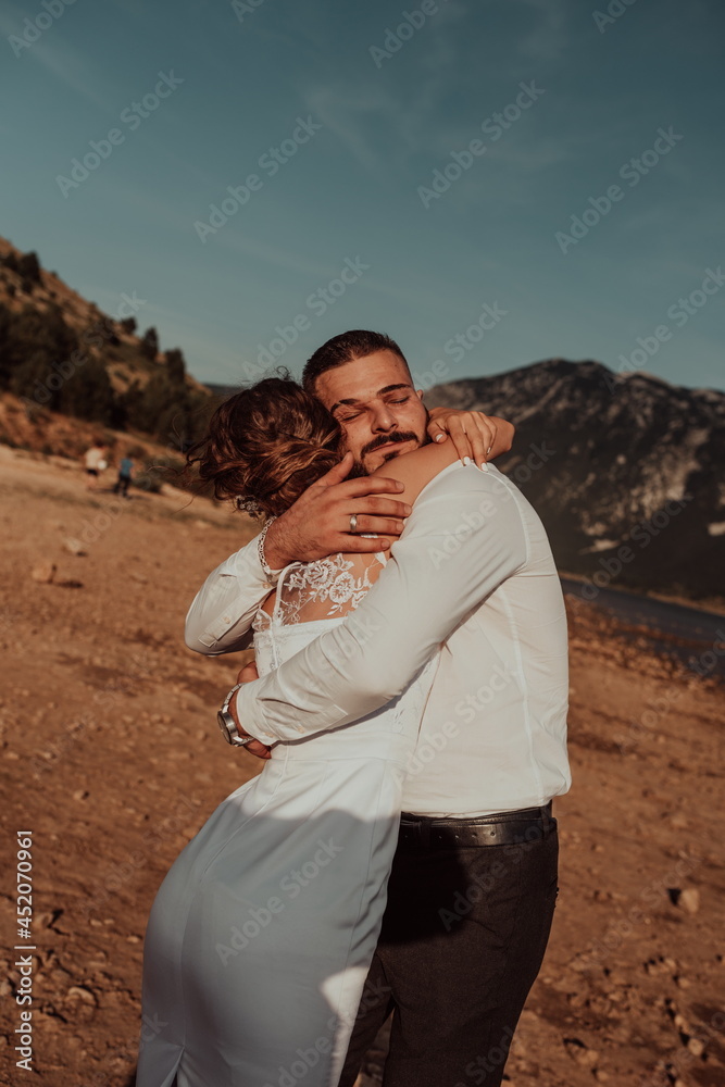 Fototapeta premium Wedding photo. A young married couple having fun and dancing by a large lake.Selective focus