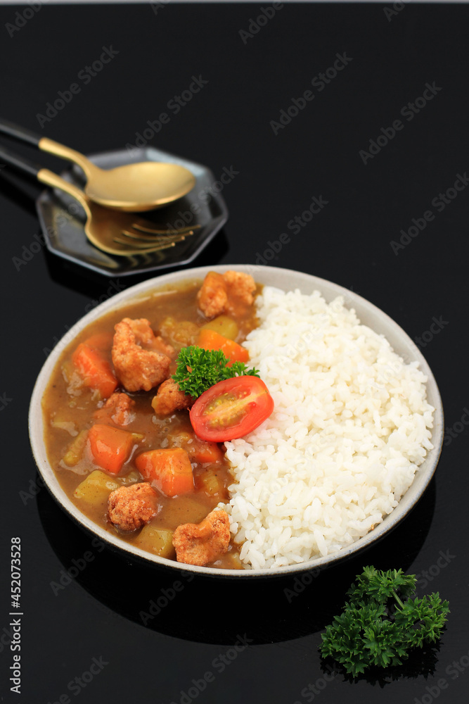 Curry with Rice - Japanese Food Style. Top View on Ceramic Plate Black Wooden Table  with Potato and Carrot Dice, Copy Space for Text