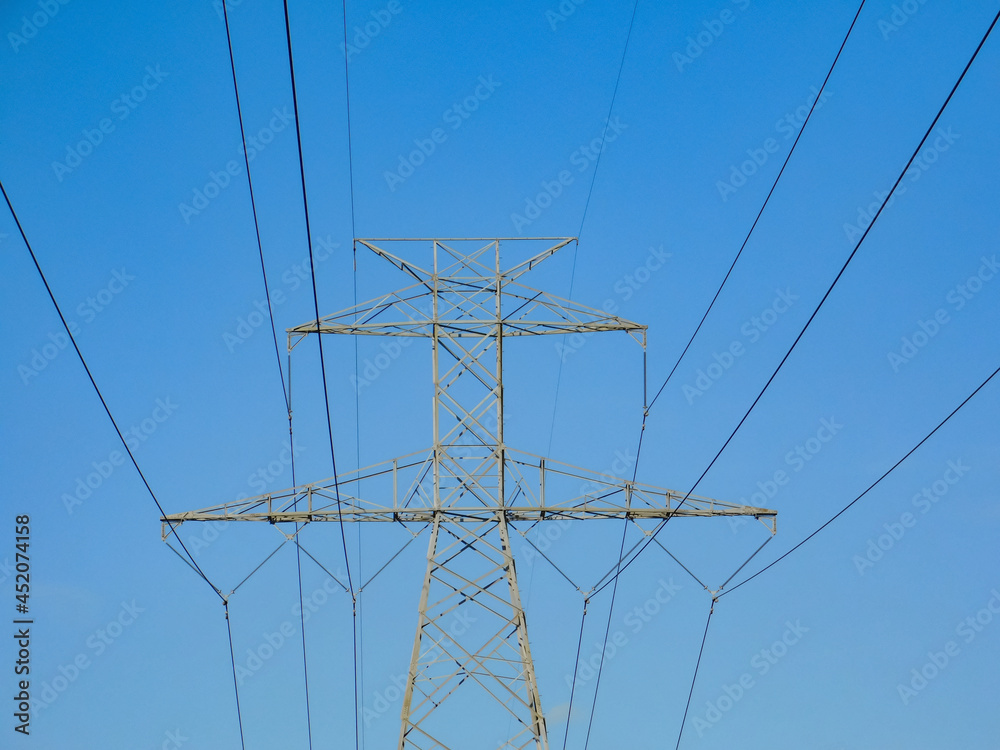 Top half of Powerline tower structure, centered against blue sky in direct sunlight Top half of Powerline tower structure, centered against blue sky in direct sunlight