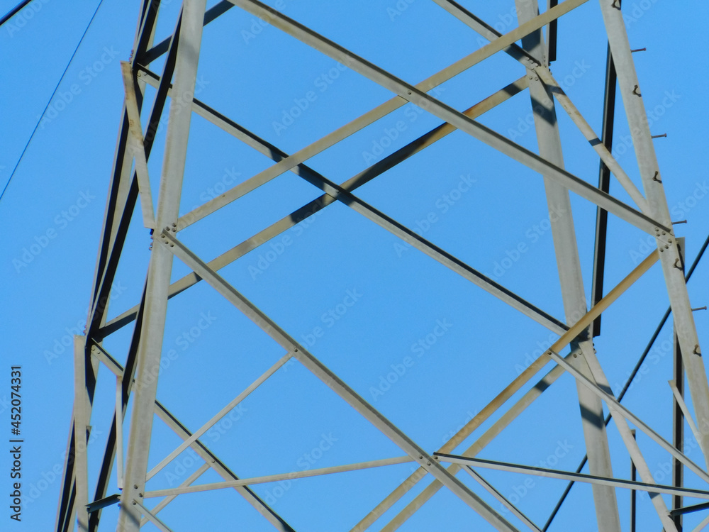 Fototapeta premium Close up of Powerline tower structure against clear sky in direct sunlight