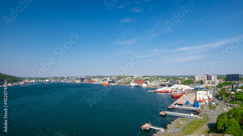 St. John's, Newfoundland, Canada - September 2021: Harbor view of the downtown area of St. John's with large offshore oil supply vessels and salmon farming feed transport boats tied to the dock.  