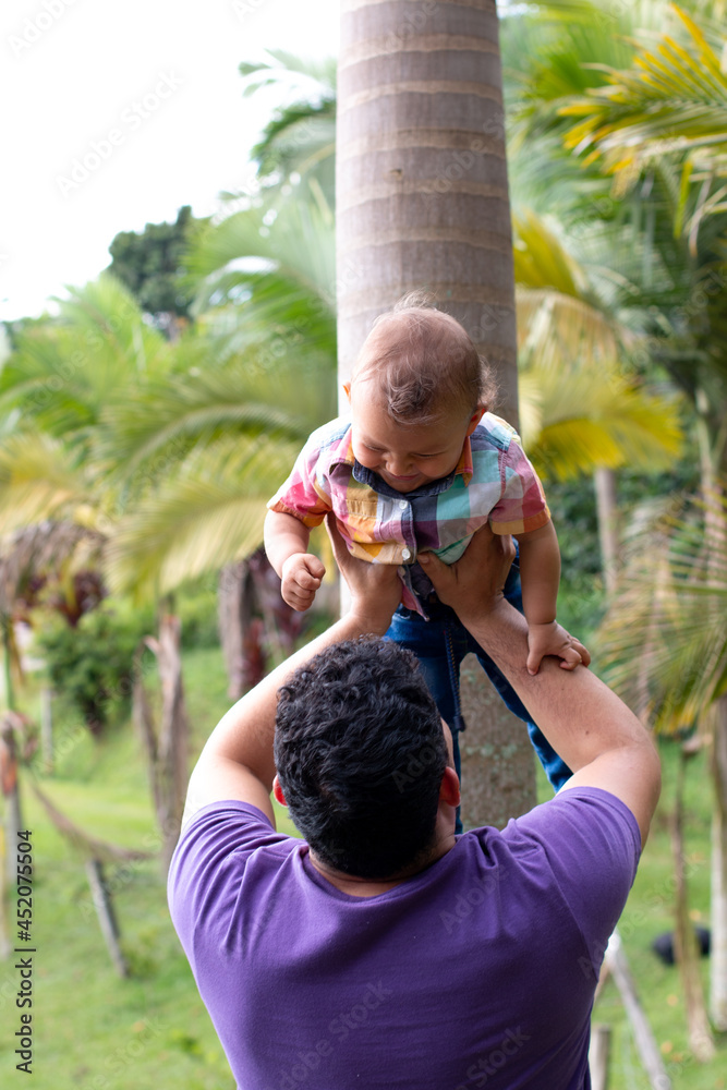 The father lifts his son above his head as they look into each other's