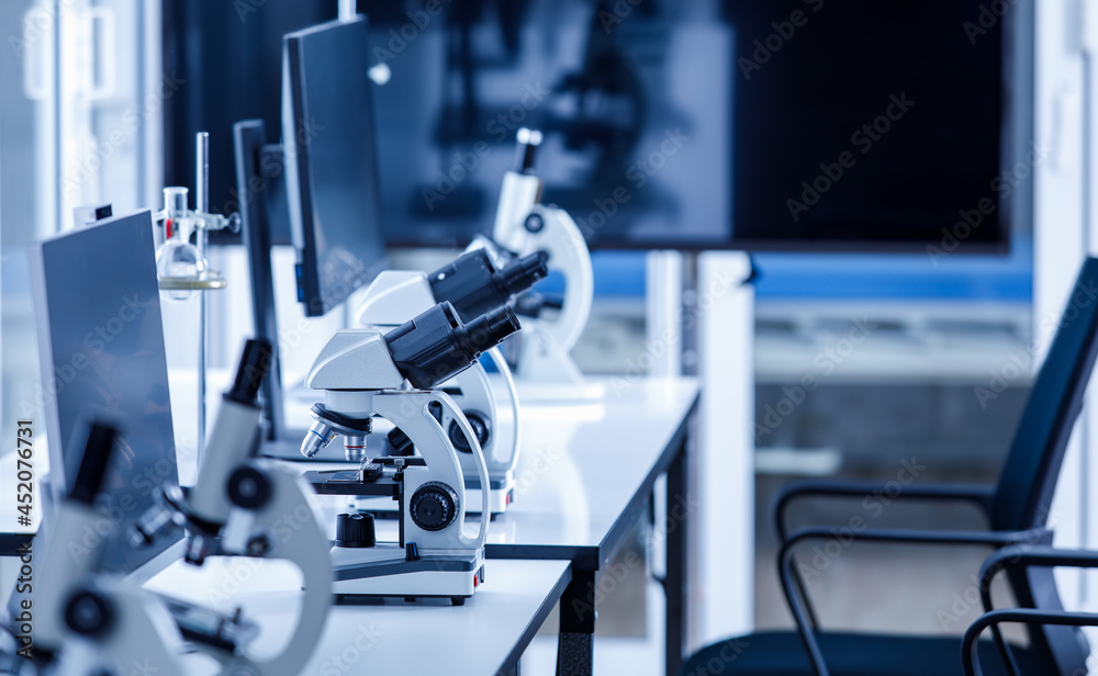 Close up shot of two eyes viewfinder scientific microscope in row of one eye microscopes line in blurred foreground on laboratory working table using for monitoring coronavirus covid 19 virus samples