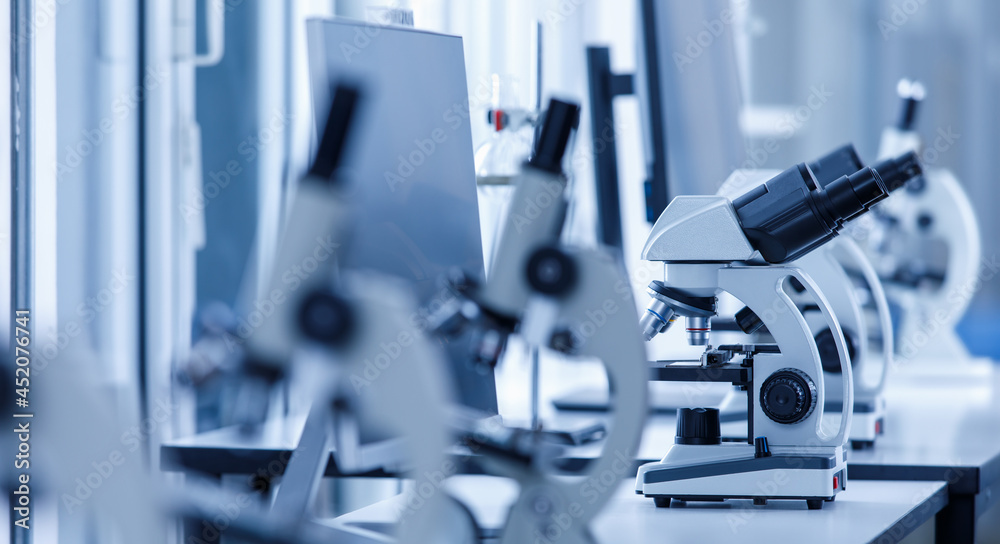 Close up shot of two eyes viewfinder scientific microscope in row of one eye microscopes line in blurred foreground on laboratory working table using for monitoring coronavirus covid 19 virus samples Close up shot of two eyes viewfinder scientific microscope in row of one eye microscopes line in blurred foreground on laboratory working table using for monitoring coronavirus covid 19 virus samples