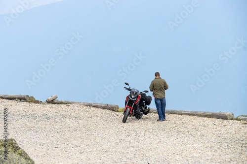Wallpaper Mural man standing next to motorcycle overlooking valley and mountains   Torontodigital.ca
