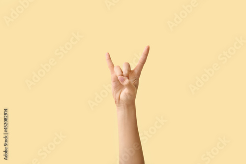 Woman showing "devil horns" gesture on color background