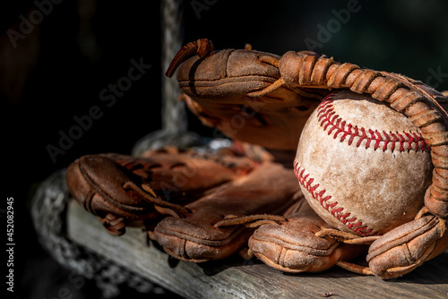 Old worn baseball in leather baseball glove in sunlight