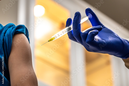 Doctor giving vaccination shot to young patient in doctor's office