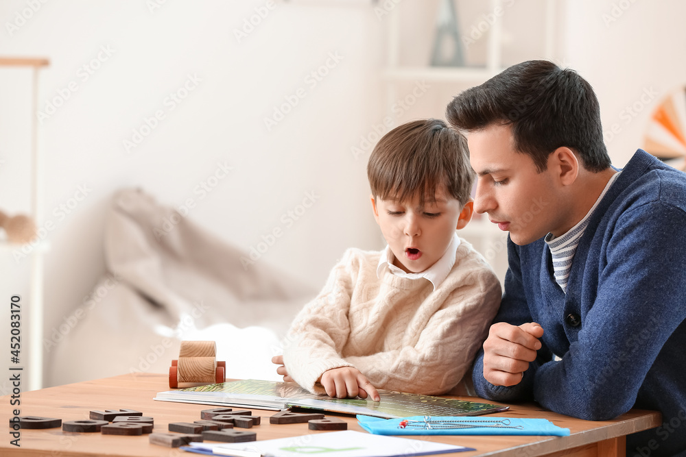 Speech therapist with little boy reading book in office Speech therapist with little boy reading book in office