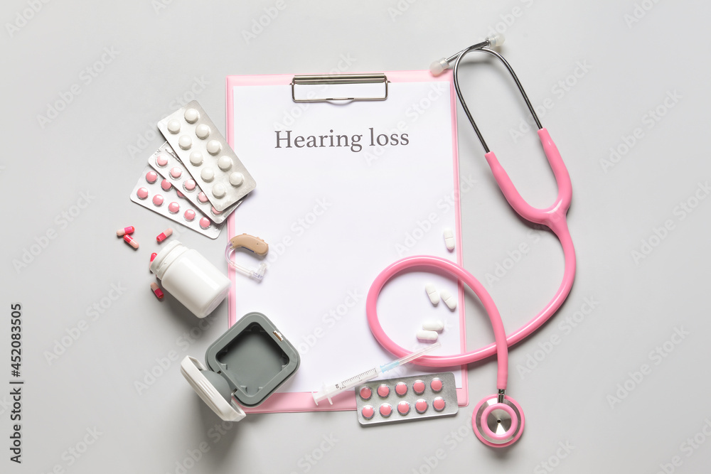 Clipboard with text HEARING LOSS, stethoscope and pills on light background Clipboard with text HEARING LOSS, stethoscope and pills on light background