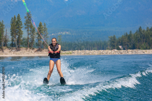 Schilderij op canvas Smiling Adult woman water skiing on a beautiful scenic mountain lake