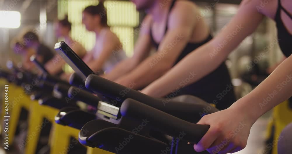 Group of athletic young people stationary bicycle doing spinning at gym . A group of young women and men train on sports training equipment in a fitness gym . Healthy Lifestyle and Sport Concepts