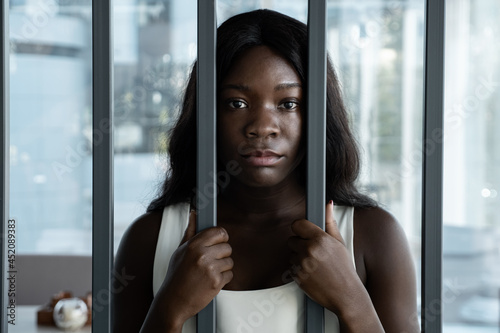 African American woman with a sad look behind iron bars.