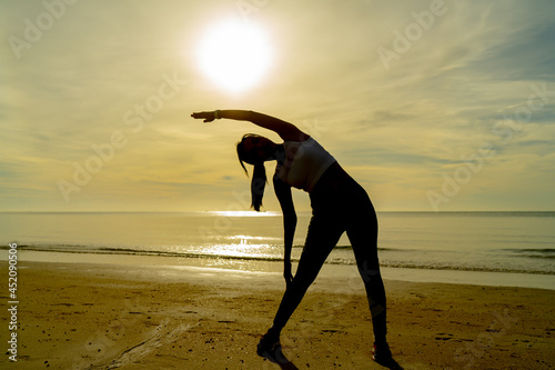 Silhouette women exercise on the beach at morning with beautiful sunrise