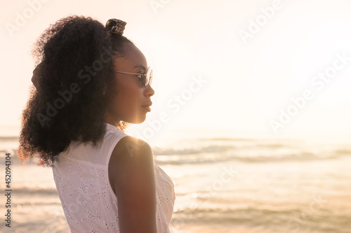 Woman enjoying sunset at the beach with the sea on background.