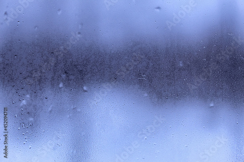 A window with raindrops on it and dark storm clouds behind in the background