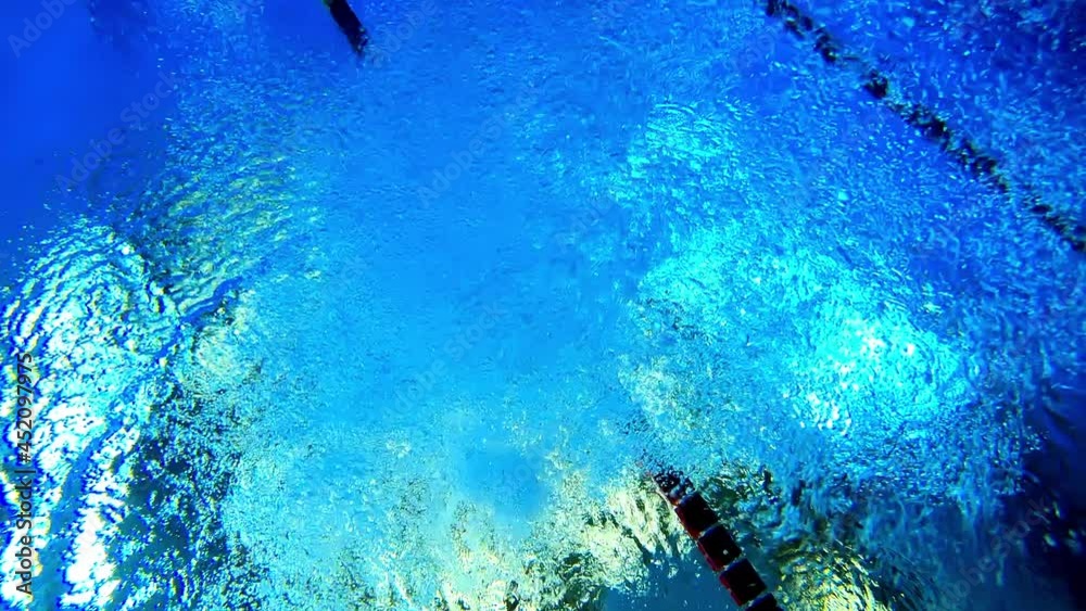 Under water view of professional female swimmer . Underwater footage of woman jumping into water . Swimmer jumping in big swimming Woman swimmer dive in water pool . Slow Motion .