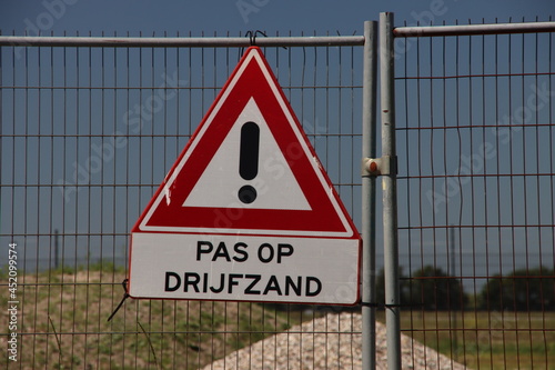 Warning sign for quicksand at construction site on fence