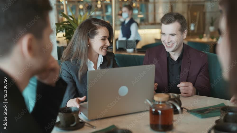 Group of suit wearing colleagues discussing working situation sitting at table in cafe with laptop. Casual coworkers having sparkling conversation in reastaurant. Concept of teambuilding, leisure. Group of suit wearing colleagues discussing working situation sitting at table in cafe with laptop. Casual coworkers having sparkling conversation in reastaurant. Concept of teambuilding, leisure.