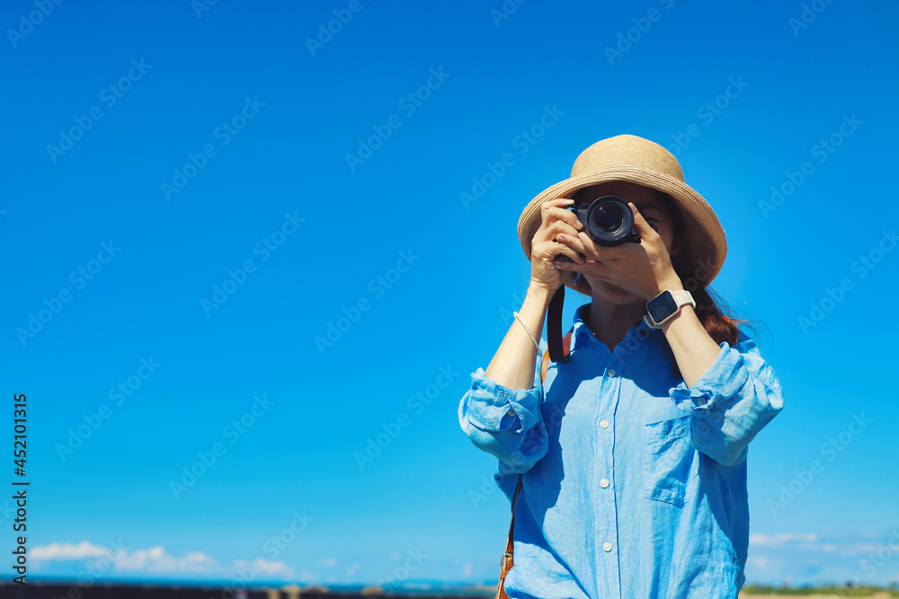 Obraz premium カメラで撮影する女性と青空