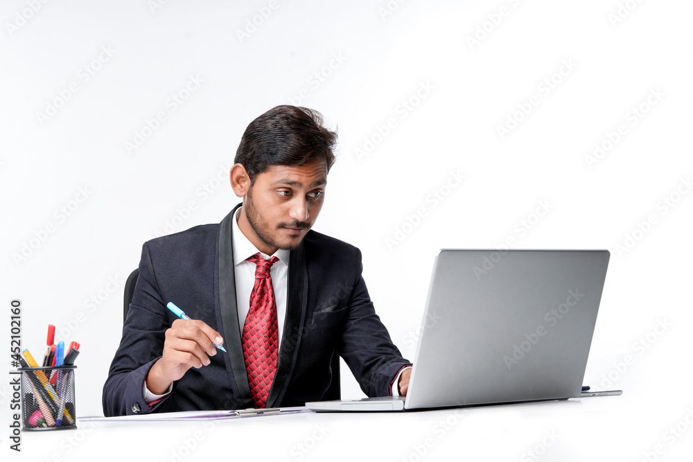 Young indian man in suit and working on laptop and writing some note at office. Young indian man in suit and working on laptop and writing some note at office.