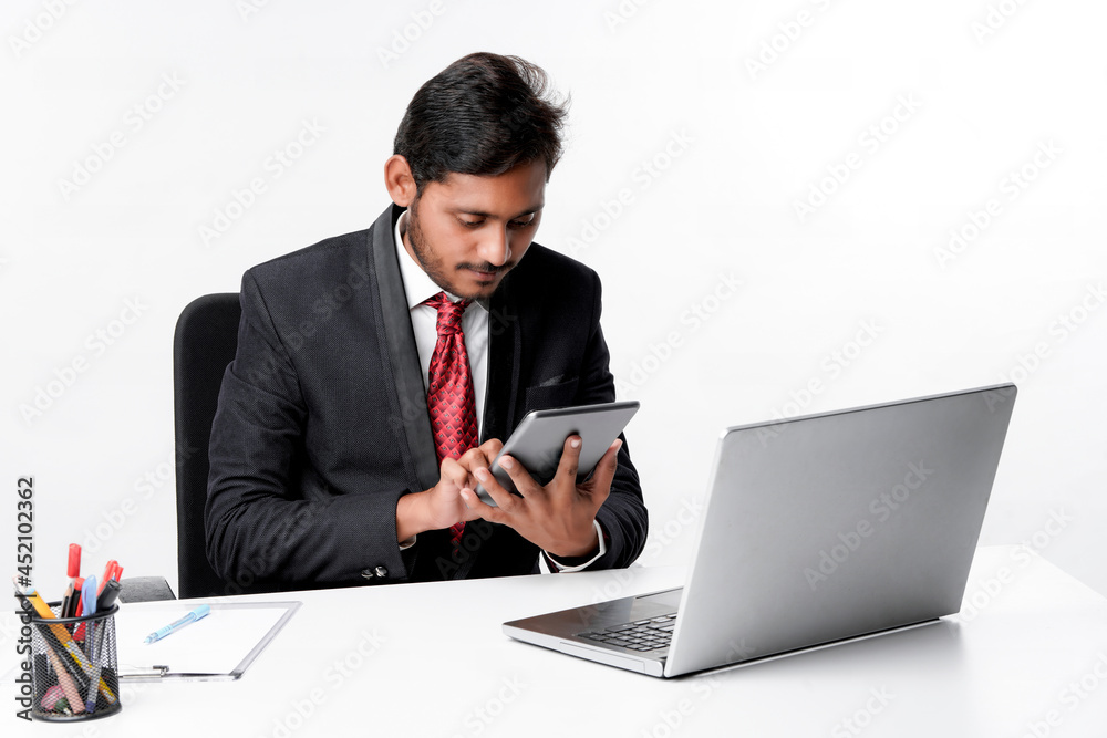 Young indian man in suit and using tablet and laptop at office Young indian man in suit and using tablet and laptop at office