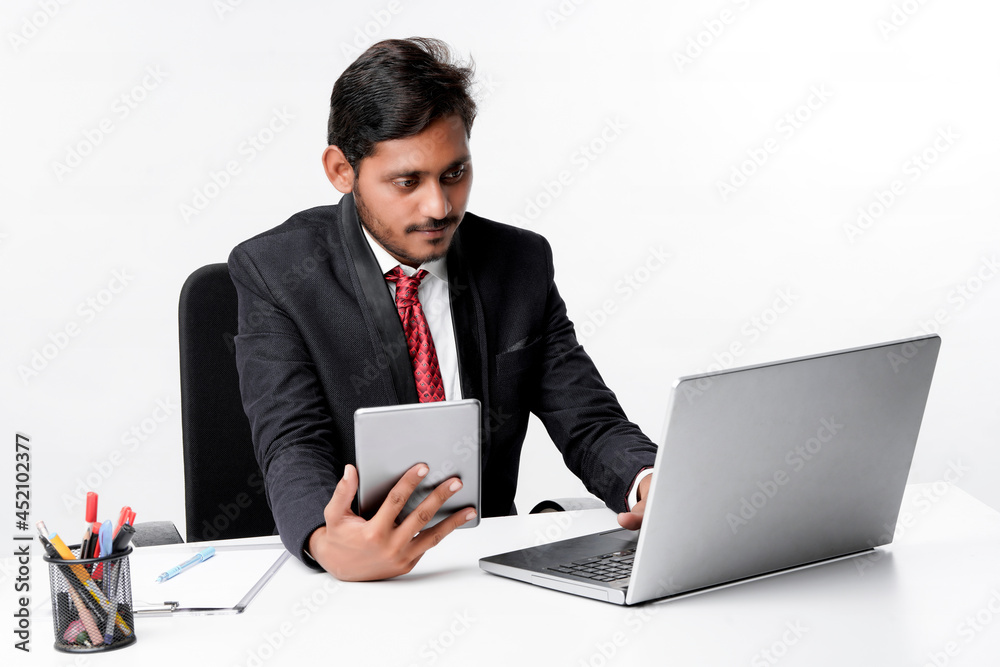Young indian man in suit and using tablet and laptop at office Young indian man in suit and using tablet and laptop at office