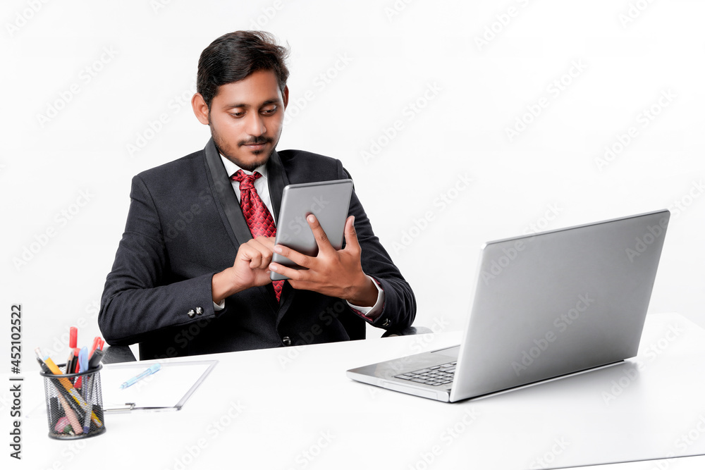 Young indian man in suit and using tablet and laptop at office Young indian man in suit and using tablet and laptop at office