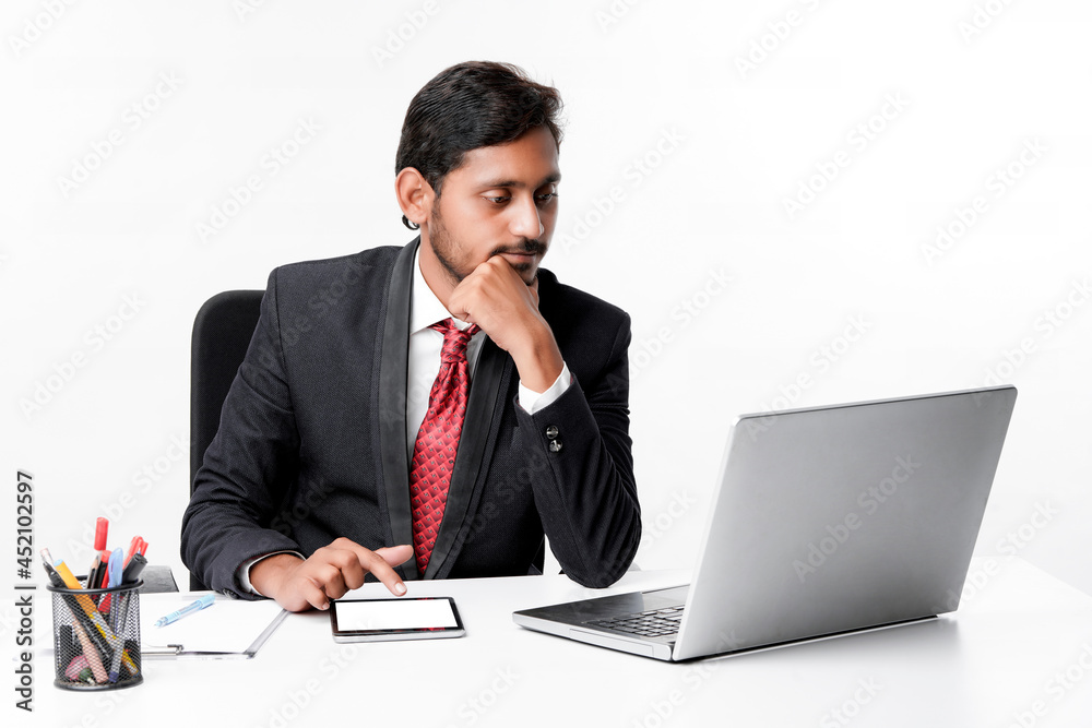 Young indian man in suit and using tablet and laptop at office Young indian man in suit and using tablet and laptop at office