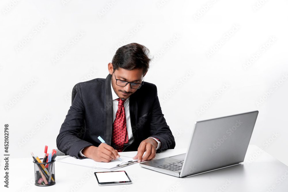 Young indian man in suit and working on laptop and writing some Young indian man in suit and working on laptop and writing some