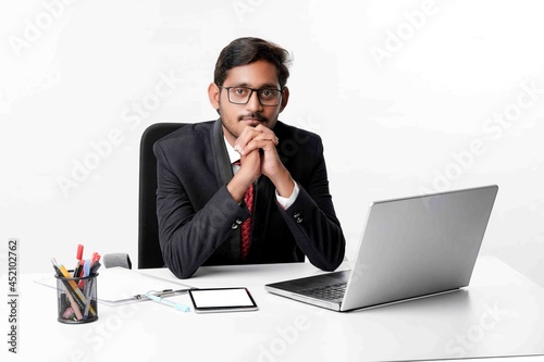 Young indian man in suit and working on laptop at office