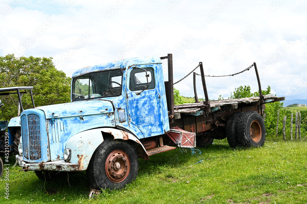 Rusty old truck on meadow. Abandoned blue car in nature. Vintage farm truck on the field.