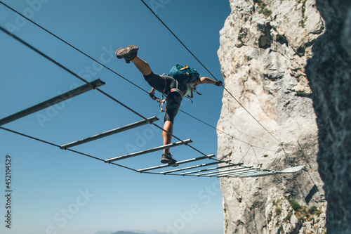 Climber posing on via ferrata  suspended wire bridge © yossarian6